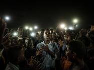 a young man at the center of crowd cries out