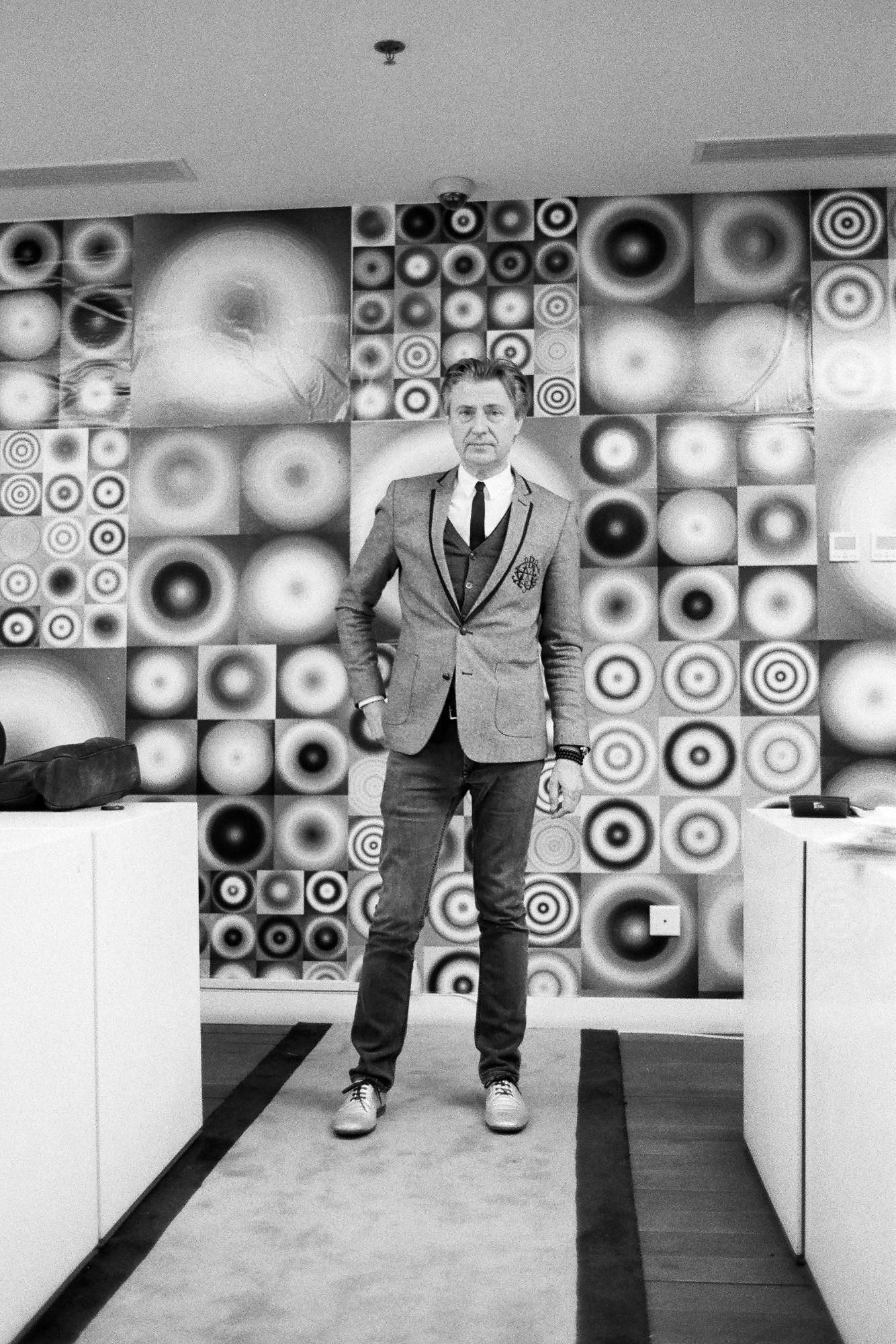 Walead Beshty photograph portrait of a man in a fitted suit in front of wall of art