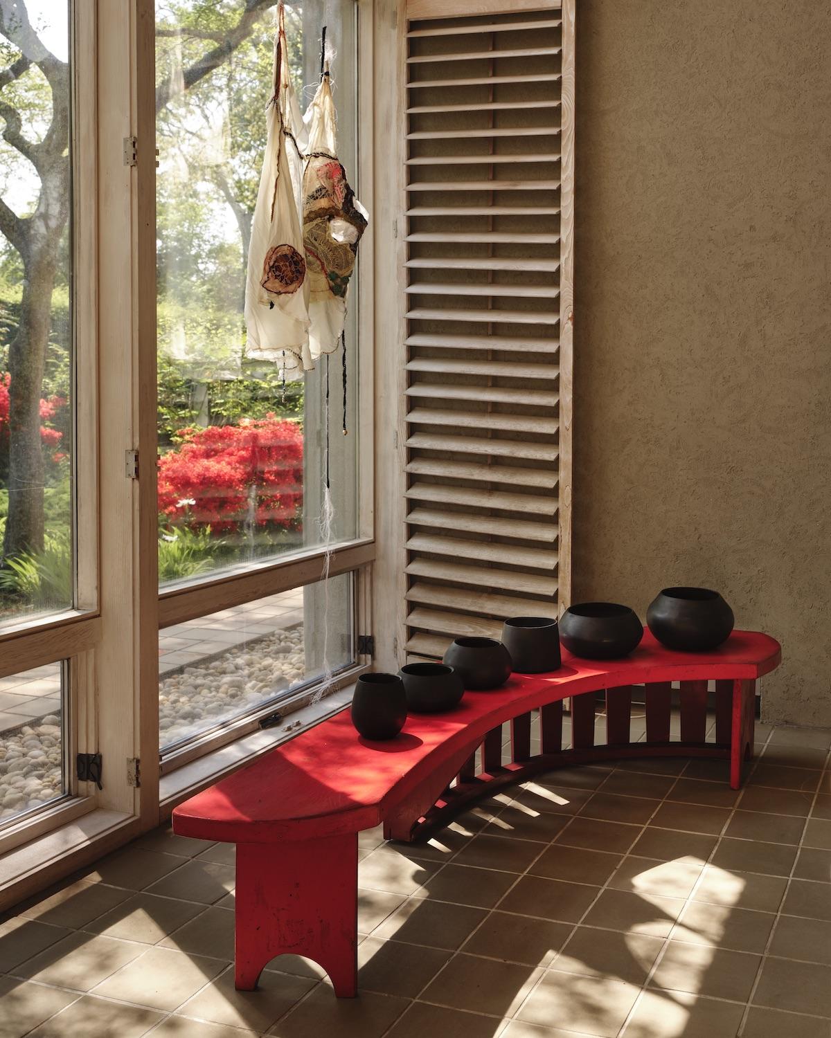 A Summer Arrangement: Object &amp; Thing at LongHouse. LongHouse, East Hampton, New York. Works pictured: [window] Sonia Gomes, Tecendo Amanhã III (2016); micaceous clay vessels by Johnny OrtizConcha arranged on a Wharton Esherick table in the collection of LongHouse.