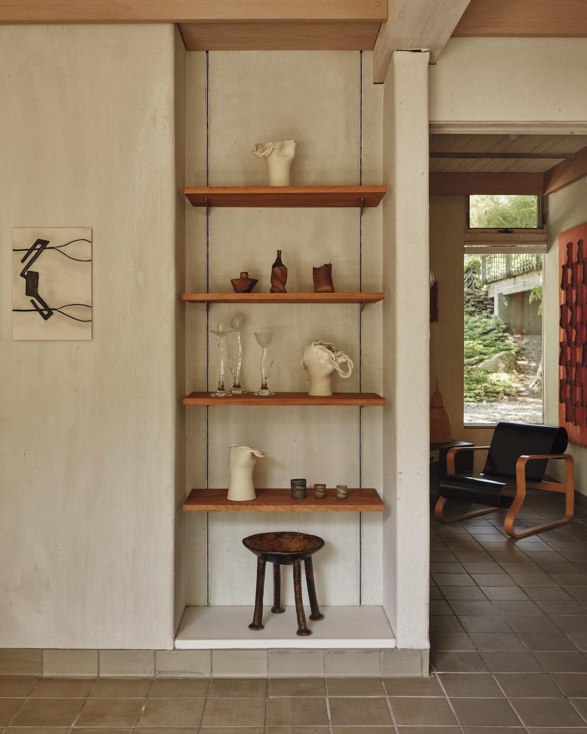 A Summer Arrangement: Object &amp; Thing at LongHouse. LongHouse, East Hampton, New York. Photo by Adrian Gaut. Works pictured: [on wall] Enrico David, Untitled (2014); [shelves] ceramics by Laird Gough, Ludmilla Balkis and Jennifer Lee; glass Giardino candleholders by Sophie Lou Jacobsen; a wooden stand from the collection at LongHouse.