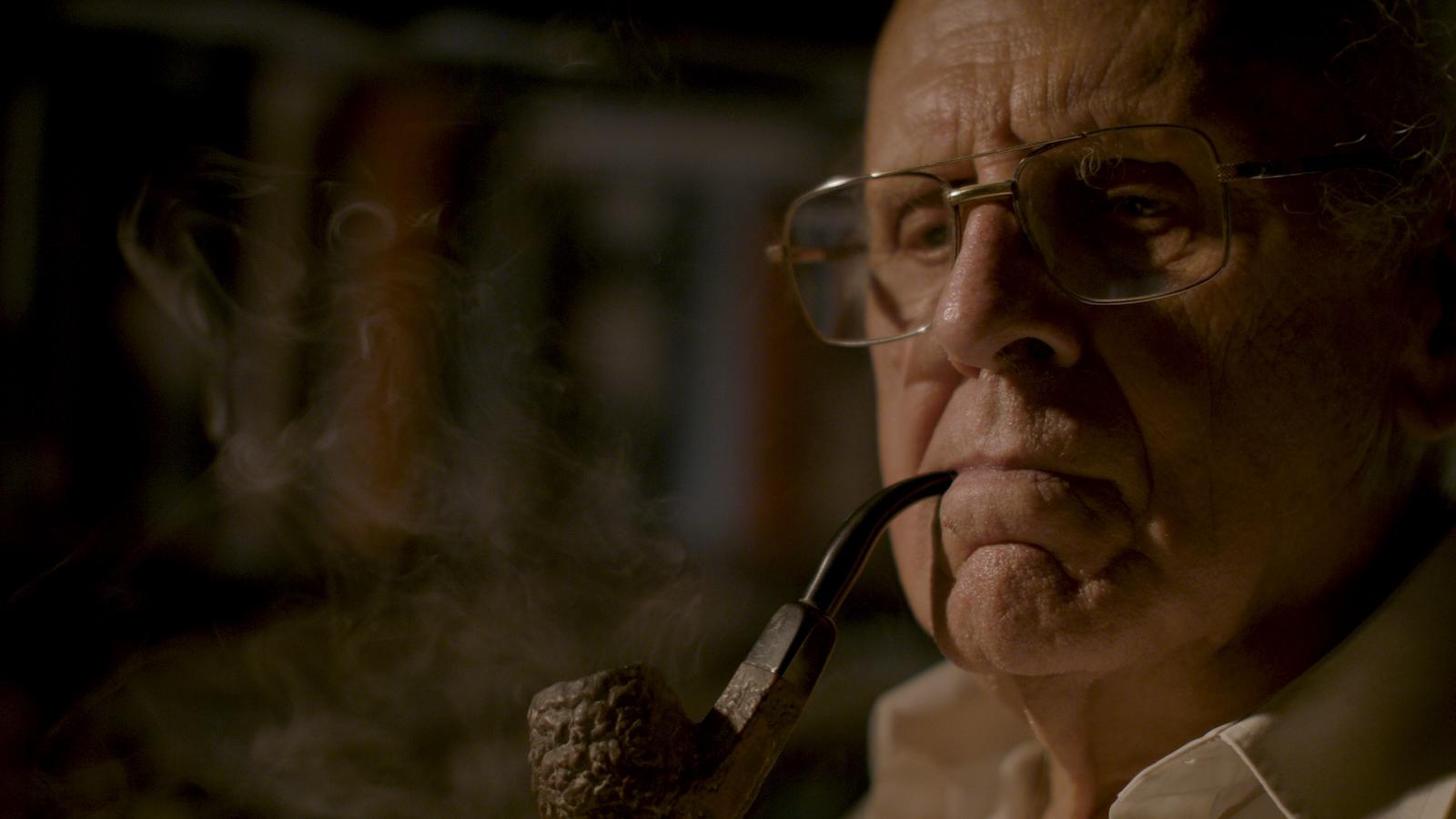 Fr Zerafa sits smoking a pipe
