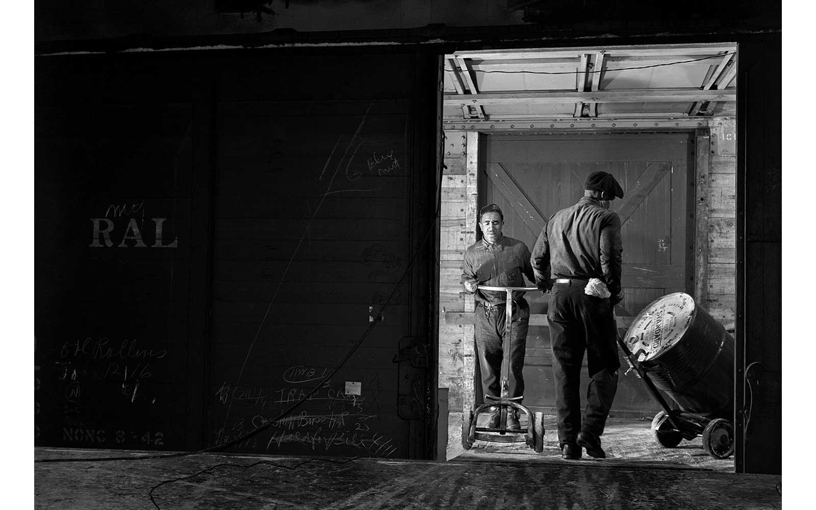 Gordon Parks, Workmen loading drums of grease into box cars for shipment.