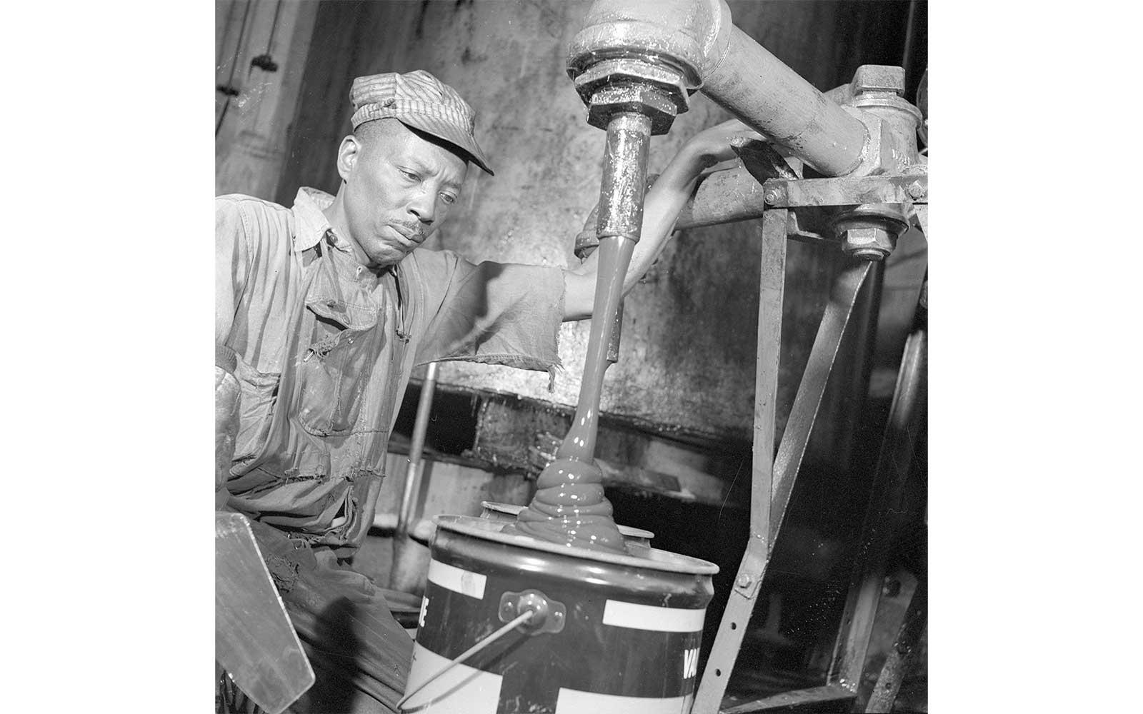 Gordon Parks, A kettle tender pouring an automotive lubricant, September 1946.