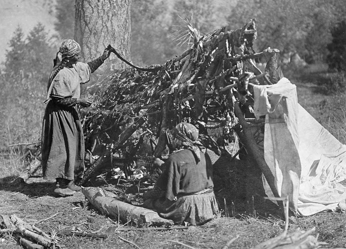 Two Salish women drying meat on a stick frame, 1910.